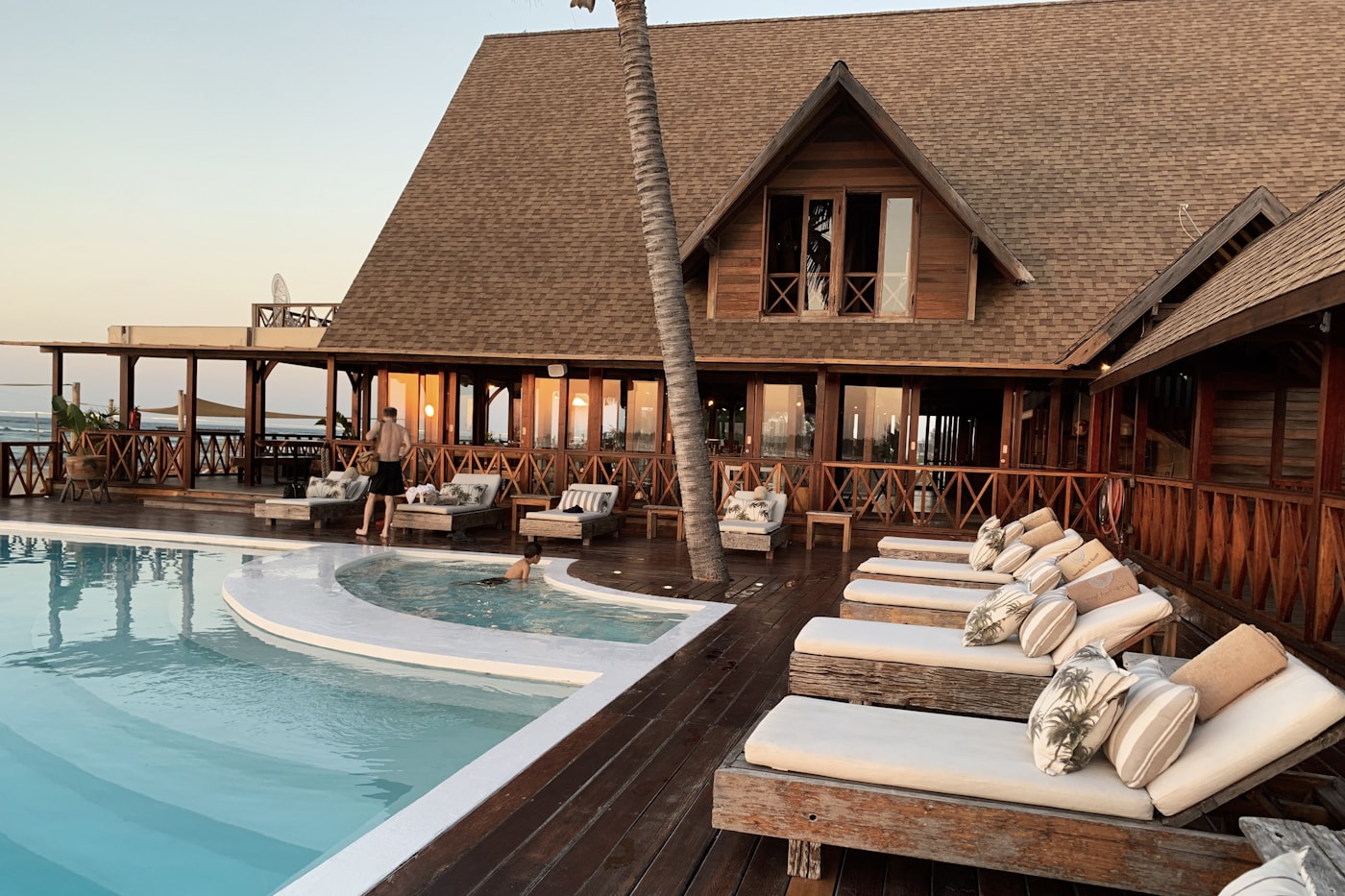 Sunlit resort pool with palms and guest seating